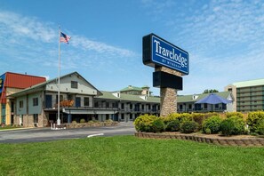 A Travelodge hotel with a large sign, a flag, and a well-maintained lawn. - Travelodge By Wyndham Pigeon Forge (Pigeon Forge)