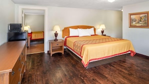 Una habitación de hotel con una cama de madera, dos lámparas de noche, una mesita de noche de madera y un televisor sobre un aparador.