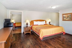A hotel room with a wooden bed, bedside lamps, a wooden dresser, and a television. - Travelodge by Wyndham Pigeon Forge (Pigeon Forge)