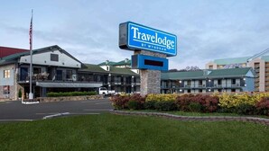 Hotel Travelodge by Wyndham con un cartel llamativo, aparcamiento y un césped bien cuidado.