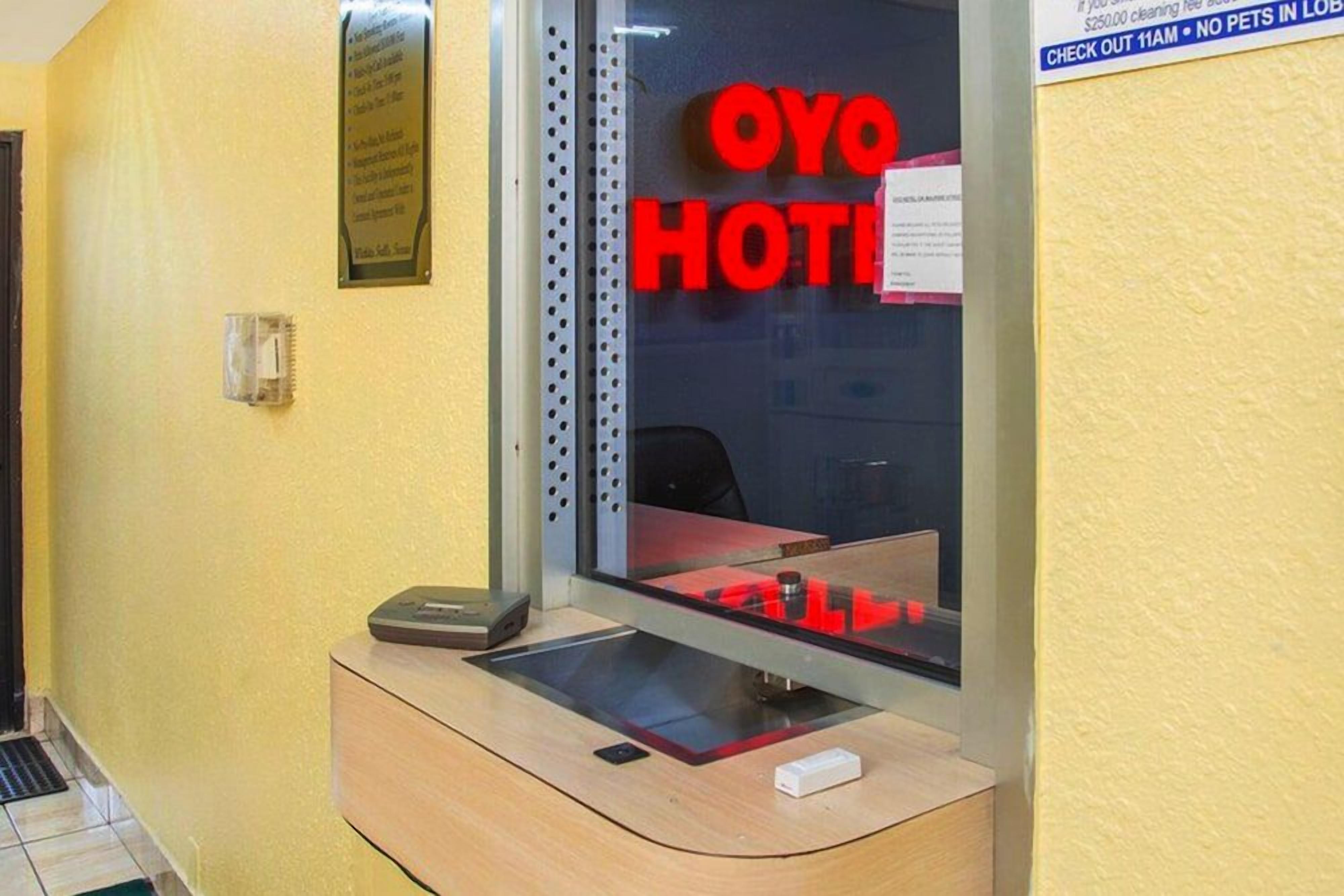 A hotel reception area with a glass partition, a reception desk, and a sign that reads 'OYO HOTEL'.