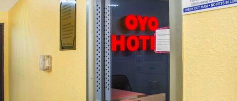 A hotel reception area with a glass partition, a reception desk, and a sign that reads 'OYO HOTEL'.