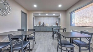 A conference room with a long table and chairs, a kitchen area in the background, and a large window with a view. - Days Inn by Wyndham Wichita Falls (Wichita Falls)