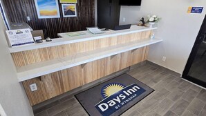 A reception area with a reception desk, a flat-screen TV mounted on the wall, and a sign indicating a breakfast option. - Days Inn by Wyndham Wichita Falls (Wichita Falls)