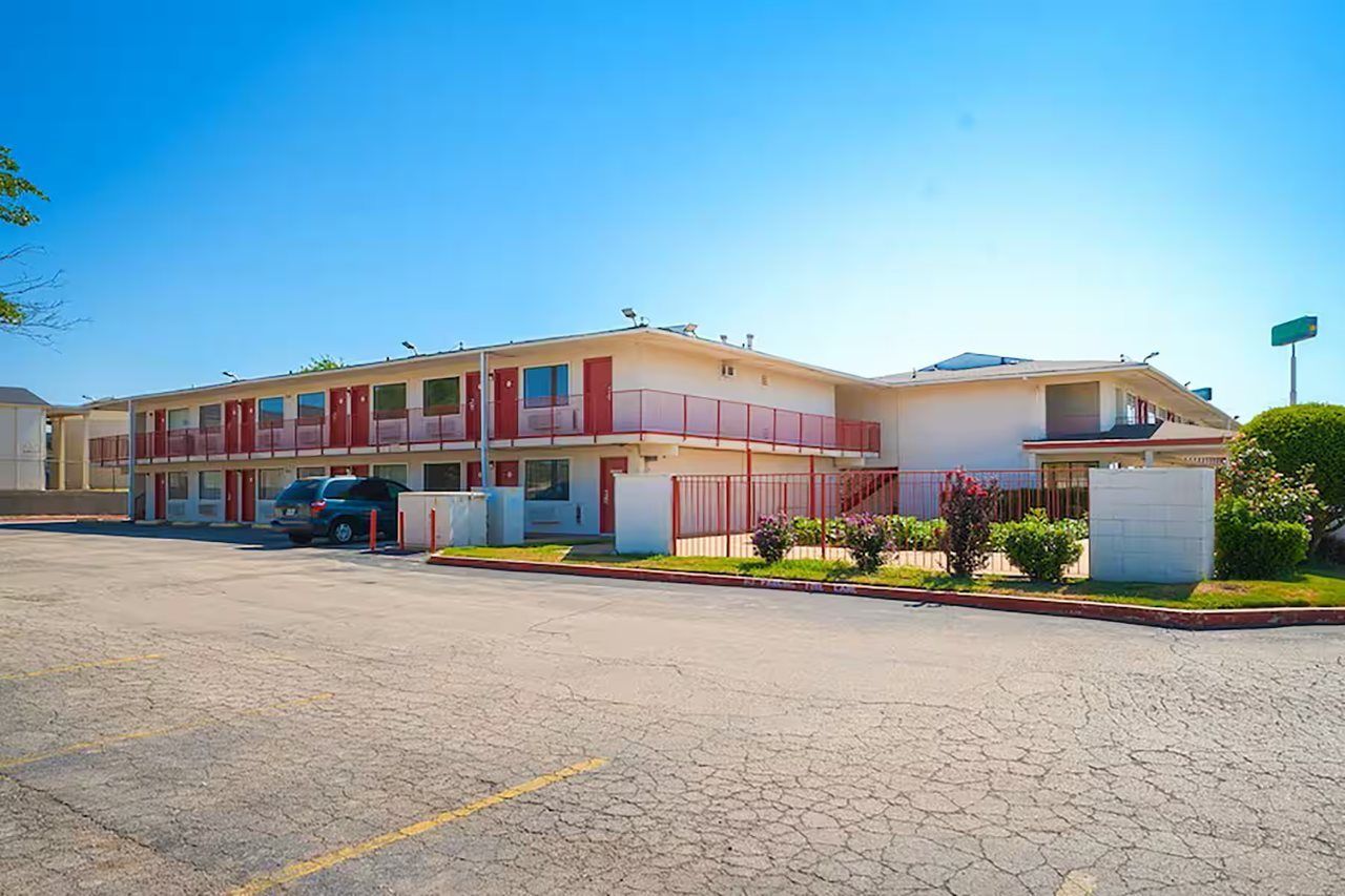 A motel with a two-story structure, a parking lot, and a small garden area.