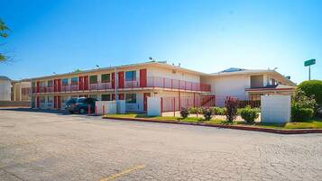 A motel with a two-story structure, a parking lot, and a small garden area.