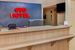 Una recepción de hotel con un letrero que dice 'OYO HOTEL' y un monitor de computadora.