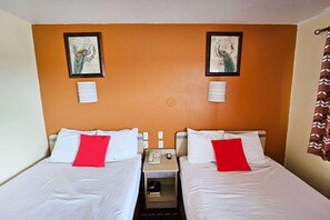 A hotel room with two beds, a nightstand with a phone and lamp, and two wall-mounted light fixtures. - Days Inn by Wyndham Wichita Falls (Wichita Falls)