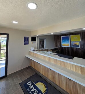 A reception desk with a digital screen, a wooden panel wall, and a welcome sign. - Days Inn by Wyndham Wichita Falls (Wichita Falls)