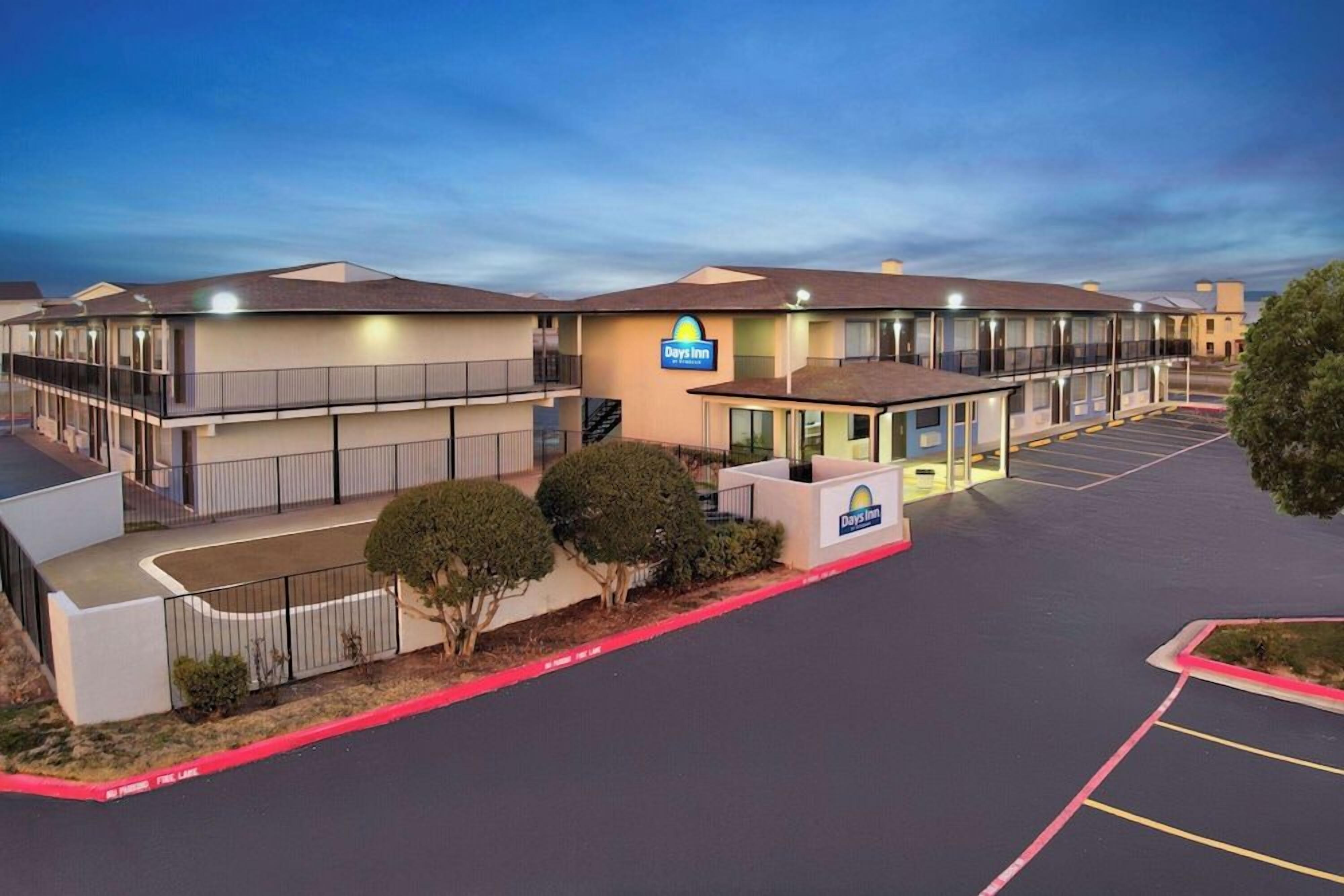 A Days Inn with a two-story building, a parking lot, and a small landscaped area with bushes.