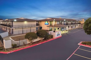 A Days Inn with a two-story building, a parking lot, and a small landscaped area with bushes. - Days Inn by Wyndham Wichita Falls (Wichita Falls)
