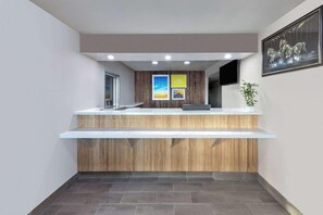 Un mostrador de recepción con paneles de madera, una encimera blanca y un cuadro en la pared.