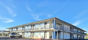 Un motel de varios pisos con techo plano, balcones y estacionamiento.
