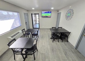 A conference room with tables and chairs, a television screen, and a decorative wall piece. - Days Inn by Wyndham Wichita Falls (Wichita Falls)