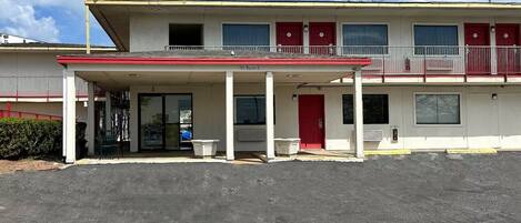 A motel with a covered parking area, a single-story structure, and a red and white color scheme.