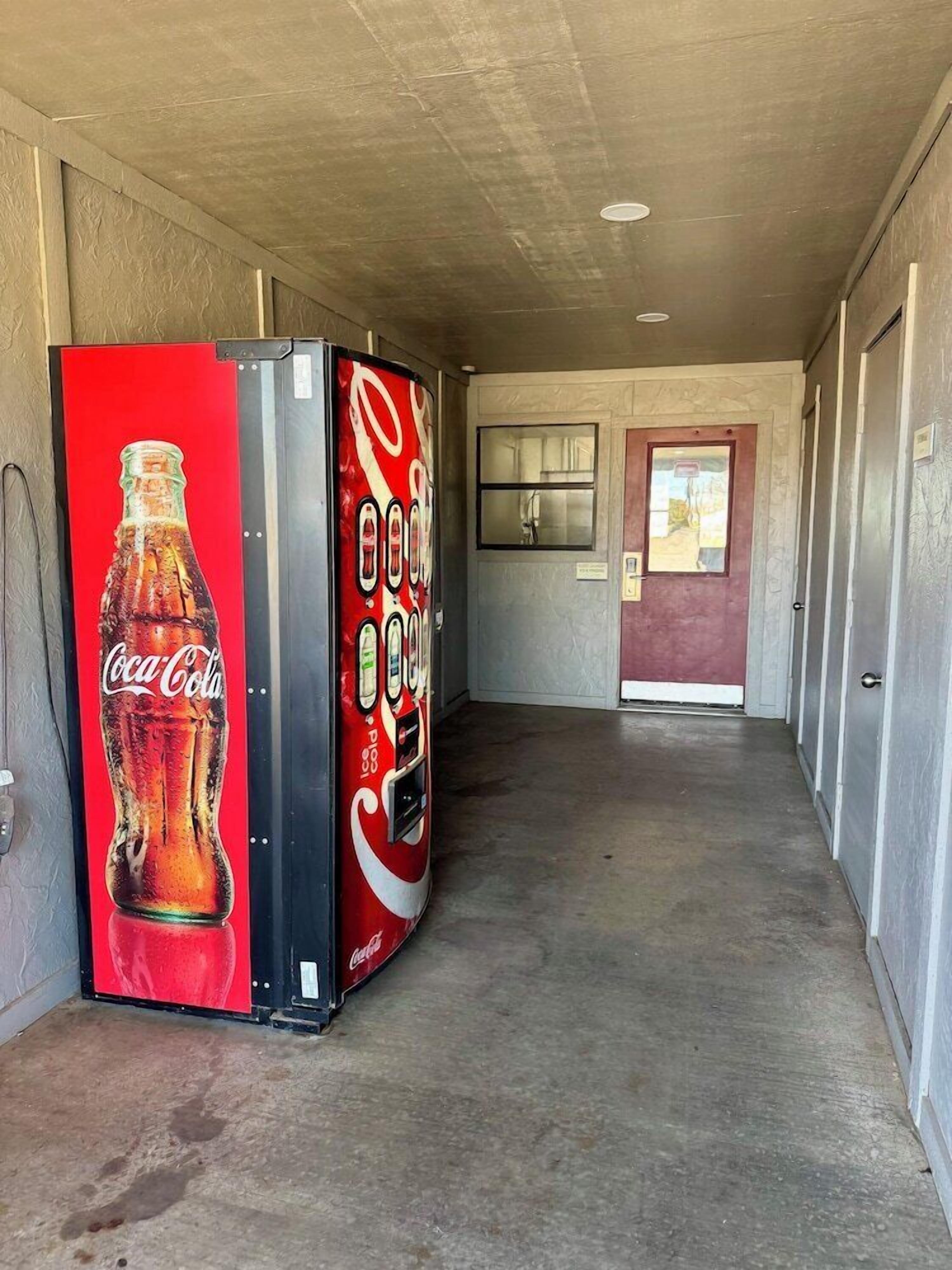 Ein Korridor mit einer Coca-Cola-Getränkeautomaten und einer Tür am Ende.