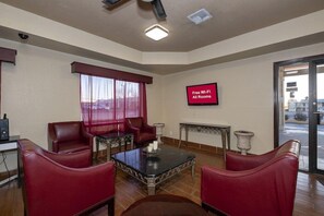 A hotel room with a TV displaying 'Free Wi-Fi All Rooms,' a fireplace, a dining table, and red leather chairs.