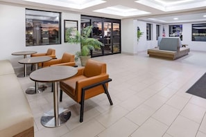 A modern lobby with a seating area, a large window, and a door leading outside. - Wingate by Wyndham Fishkill Hotel (Fishkill)
