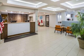 A hotel lobby with a reception desk, seating area, and a kitchenette in the background. - Wingate by Wyndham Fishkill Hotel (Fishkill)