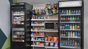 Ein Verkaufsautomatenbereich mit verschiedenen Snacks, Getränken und einer Mikrowelle.