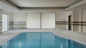 Ein Hallenbad mit Sitzbank, gefliesten Wänden und einer Tür.