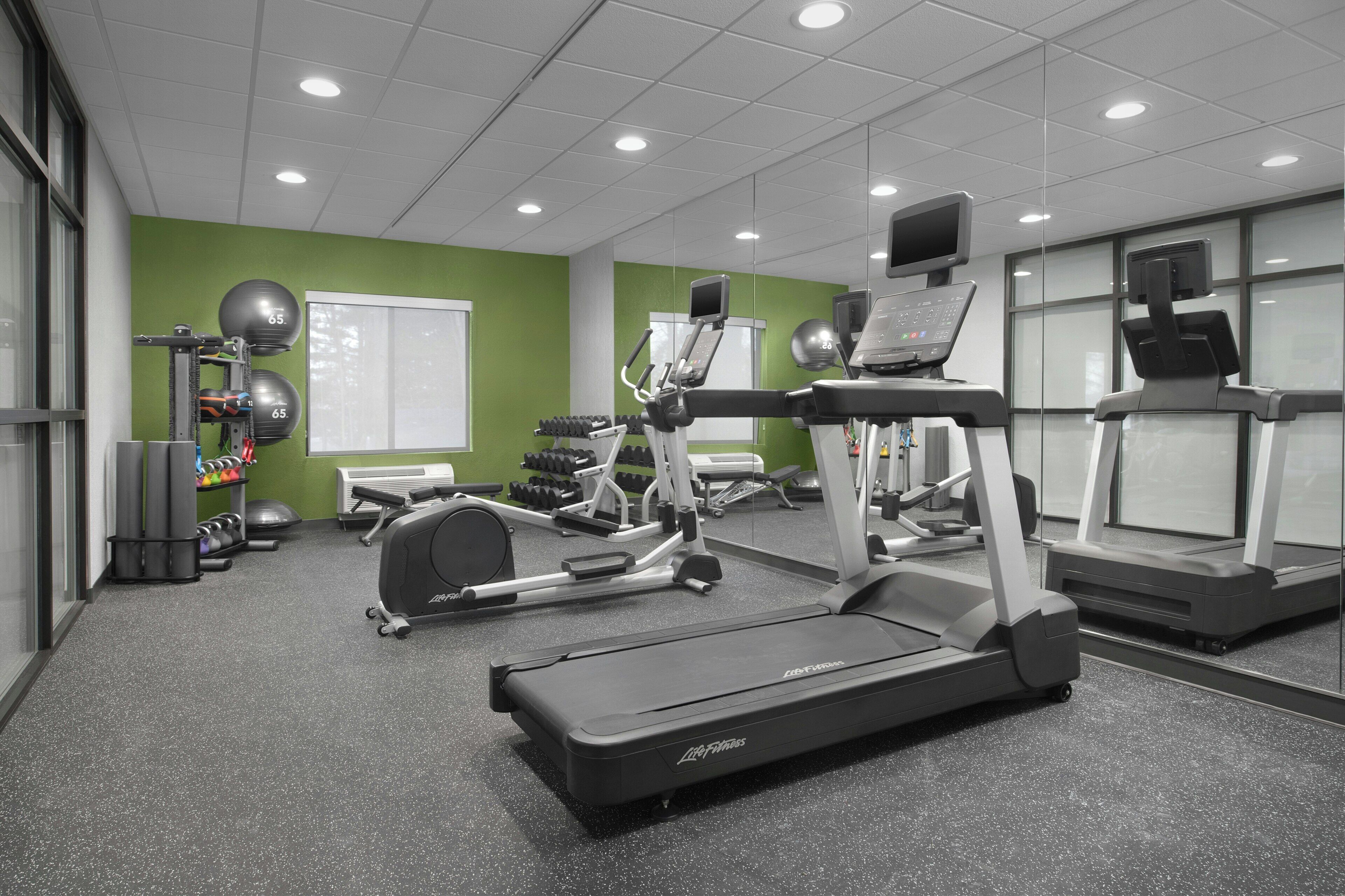 A gym with treadmills, elliptical machines, and free weights.