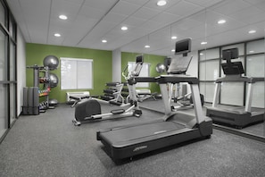 Et fitnesscenter med løbebånd, crosstrainere og vægttræningsudstyr.