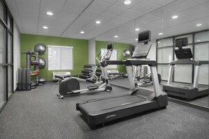 Un gimnasio con cintas de correr, elípticas y pesas libres.