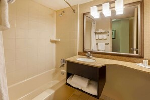 Un baño con bañera, lavamanos, espejo y toallero.