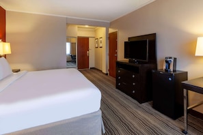 Ein Hotelzimmer mit Bett, Fernseher, Kommode und Schreibtisch.