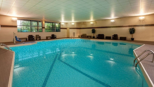 An indoor swimming pool with clear water, a tiled floor, and a ceiling with recessed lighting.
