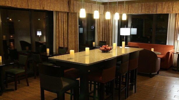 A modern dining area with a large island, multiple chairs, and pendant lighting. - Magnuson Hotel Bourbonnais (Bourbonnais)