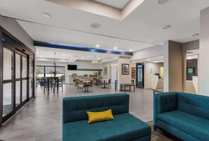 Eine moderne Hotelhalle mit Sitzbereichen, einer Rezeption und einem Essbereich.