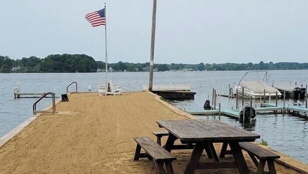 Una playa arenosa con una mesa de picnic y una bandera estadounidense.