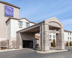 Edificio de Sleep Inn & Suites con fachada de piedra, un acceso cubierto y cielo despejado.