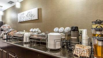 A buffet counter with various food items, a coffee maker, and a water dispenser.