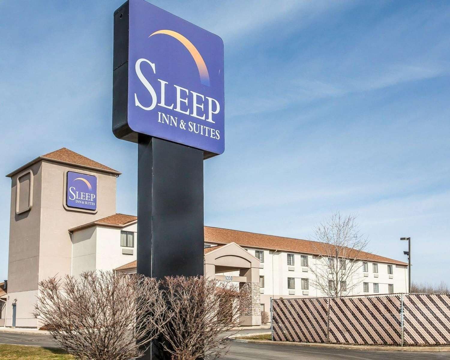 A Sleep Inn & Suites sign with a clear view of the building's entrance and a parking area.