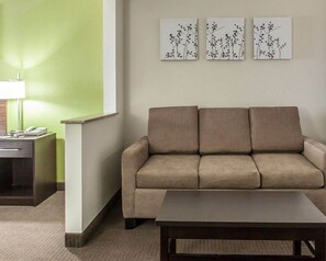 A room with a beige sofa, a small table, a lamp, and three wall-mounted artworks depicting branches. - Inn & Suites Near I-90 And Ashtabula (Austinburg)
