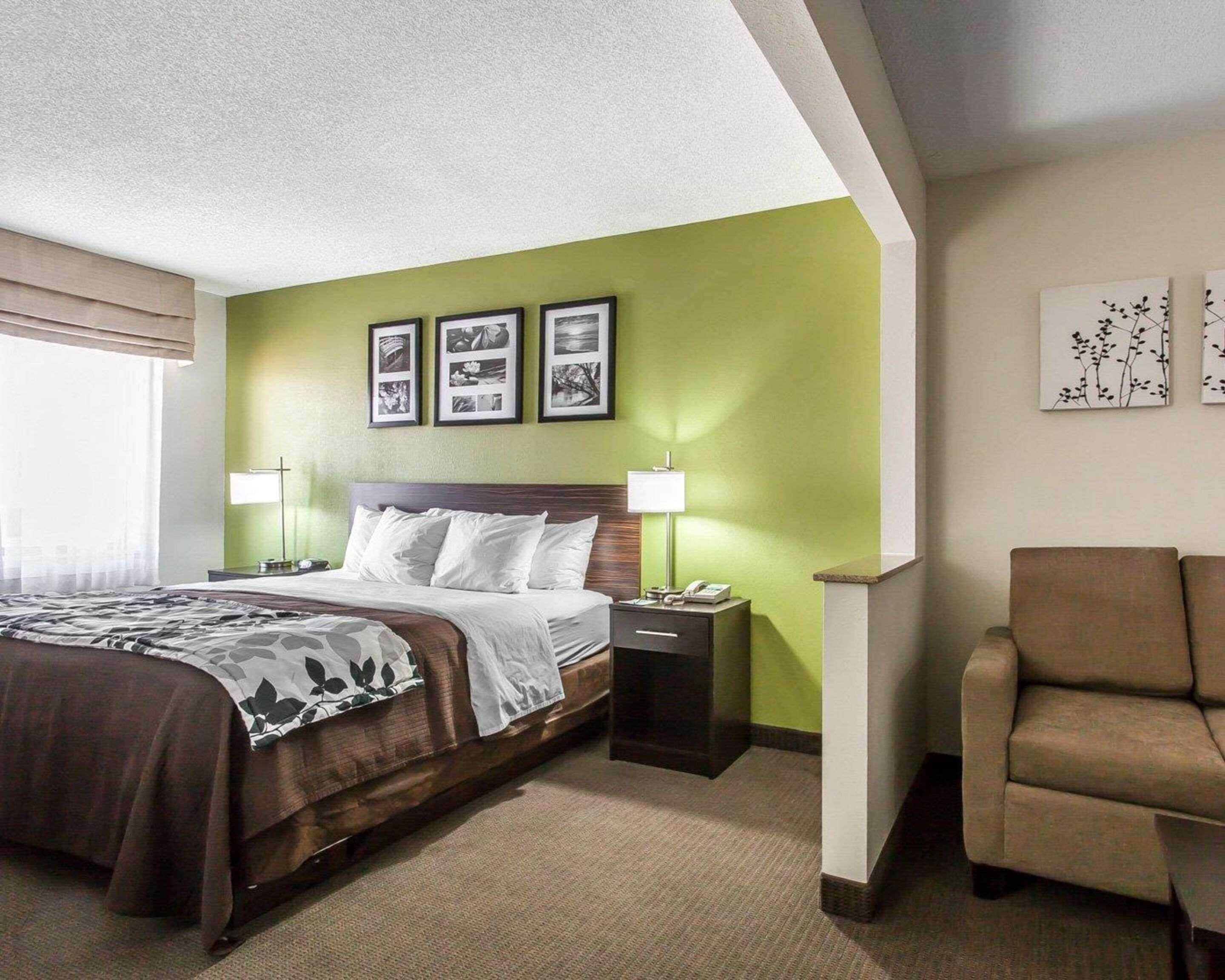 A hotel room with a large bed, two bedside tables, a chair, and artwork on the walls.