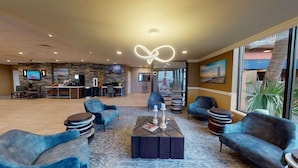 A spacious lobby with a stone wall, a bar area, and comfortable seating. - Beachfront Palms Resort Galveston, an Ascend Collection Hotel (Galveston)