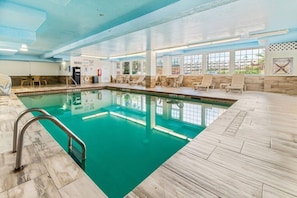 An indoor swimming pool with clear water, surrounded by lounge chairs and a tiled floor. - Beachfront Palms Resort Galveston, an Ascend Collection Hotel (Galveston)