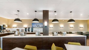 A modern restaurant with a central counter, multiple pendant lights, and a mural on the back wall. - Beachfront Palms Resort Galveston, an Ascend Collection Hotel (Galveston)