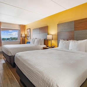 Habitación de hotel con dos camas, vista al océano y diseño moderno.