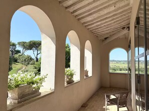 A covered balcony with arched windows overlooking a garden and countryside. - Villa Bergamotti: Toscaanse elegantie en verwarmd zwembad (buonconvento)