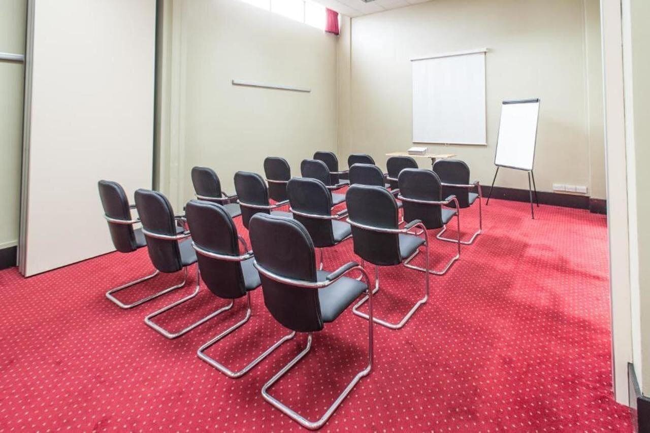 A conference room with rows of chairs, a whiteboard, and a carpeted floor.