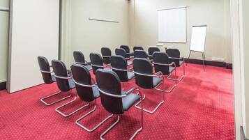 A conference room with rows of chairs, a whiteboard, and a carpeted floor.
