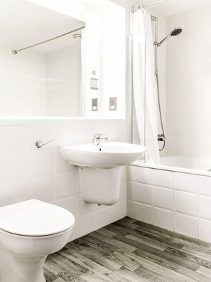 Et badeværelse med toilet, vask og brusebad.