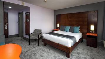 A hotel room with a large bed, a chair, a small table, and two bedside lamps.