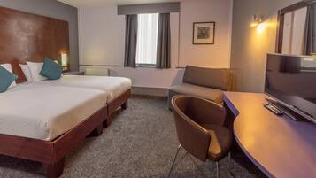 A hotel room with two beds, a TV, a desk, and a chair.