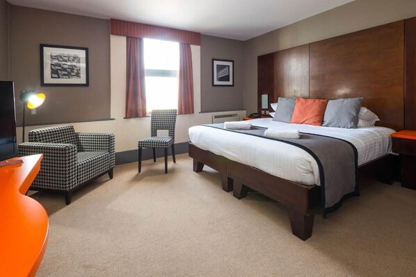 A hotel room with a large bed, a chair, a desk, and a lamp. - Sheffield Metropolitan Hotel by Belvilla (Sheffield)